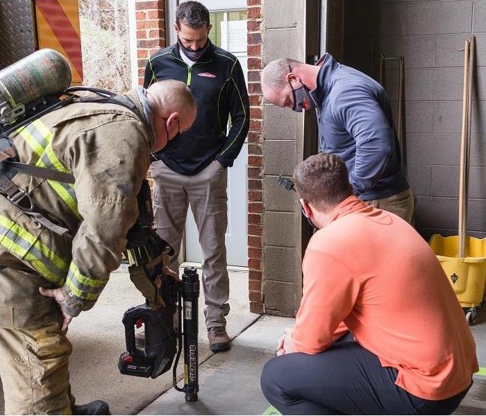 fireman and SERVPRO techs looking at fire equipment. Fireman is in gear