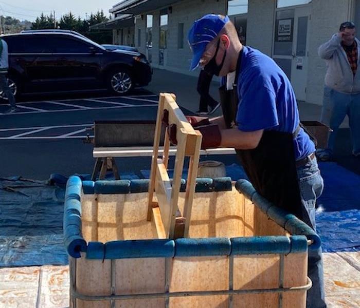 Male in a blue shirt moving wood into a crate