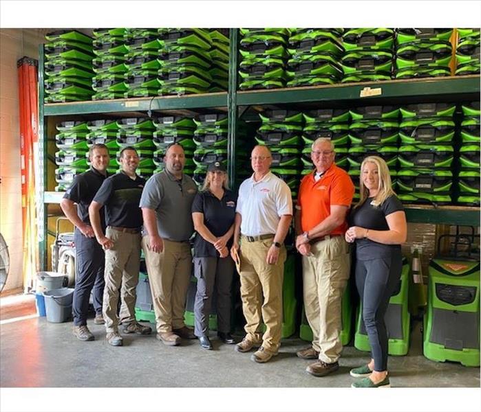 Owners plus key employees posing in the warehouse with air movers in the background