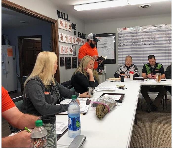 SERVPRO employees attending weekly meeting.  Sitting around tales while man addresses group