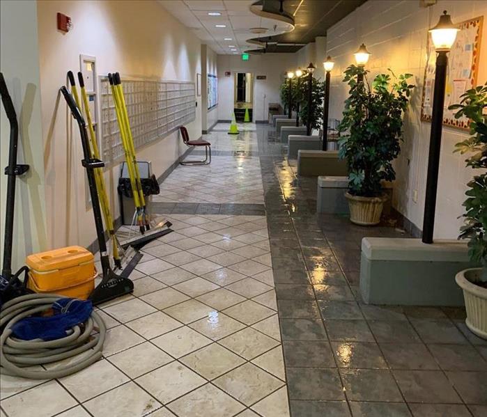 SERVPRO cleaning equipment in a tiled hallway by mailboxes