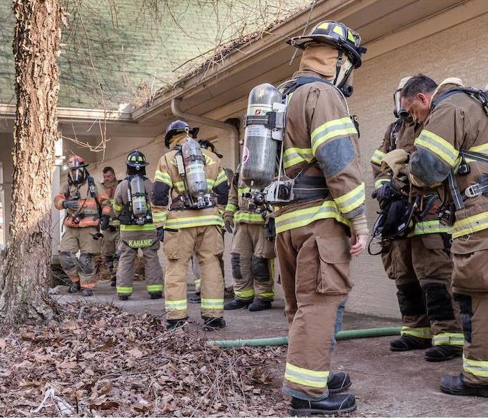 Firefighters standing outside of a tan home