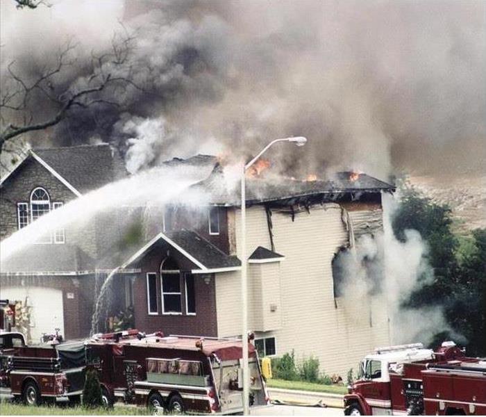 burning home; fire trucks extinguishing flames